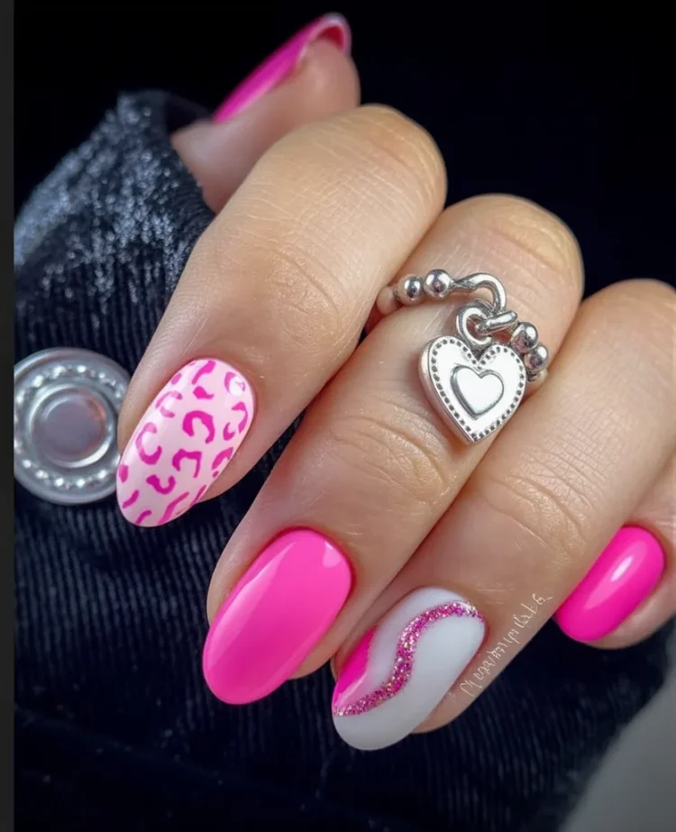 Hot pink almond nails with a pink leopard-print accent and a white nail with a glitter wave.