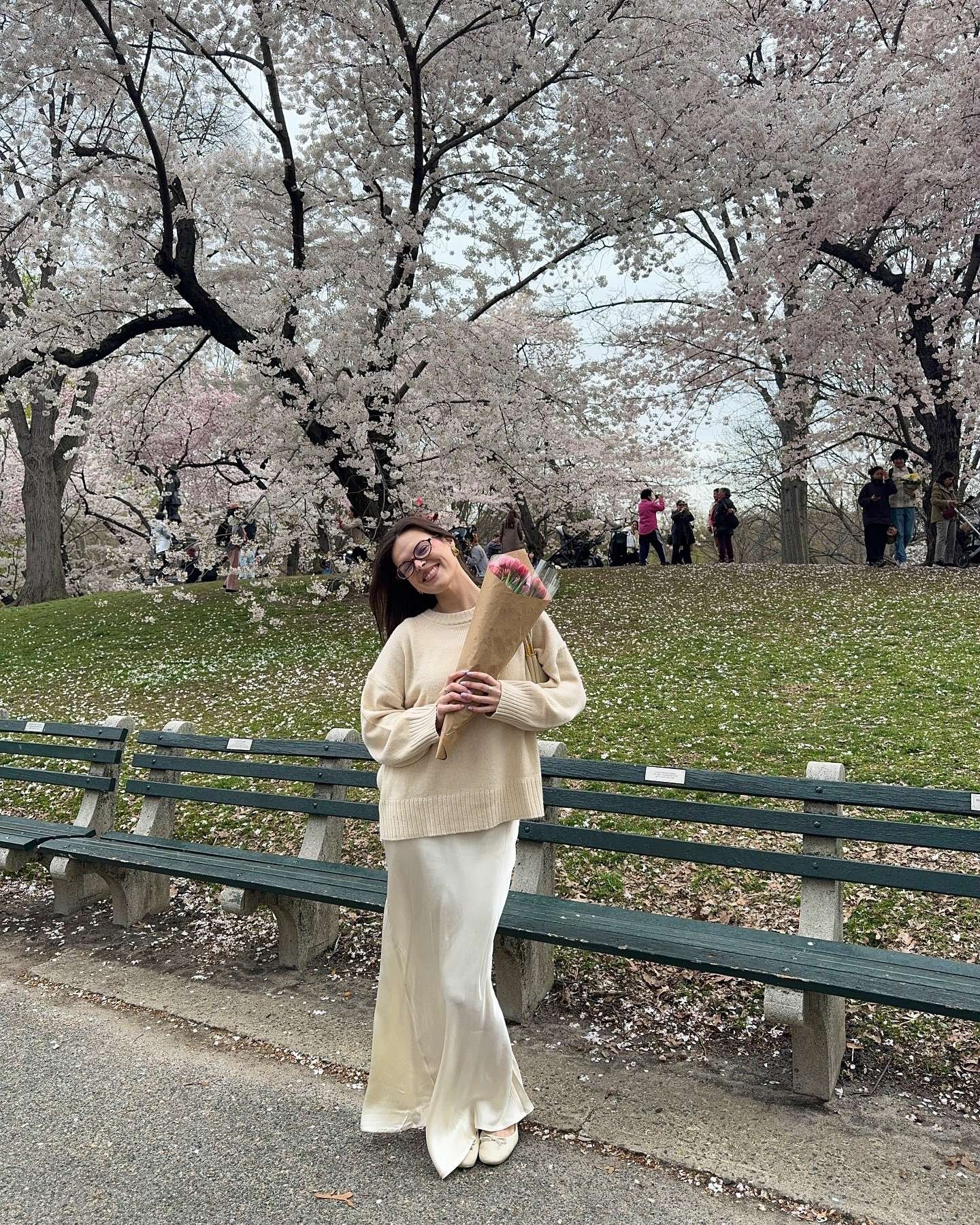 Neutral sweater and skirt under cherry blossoms