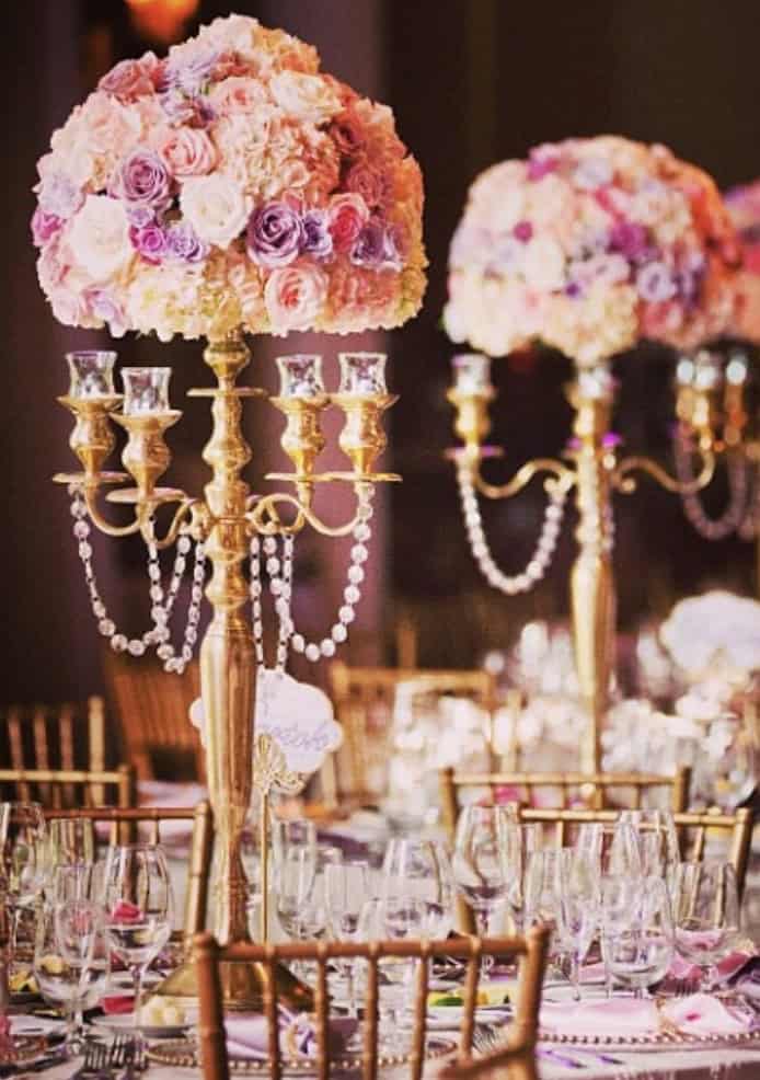Lavish floral centerpieces with pink and purple roses on golden stands