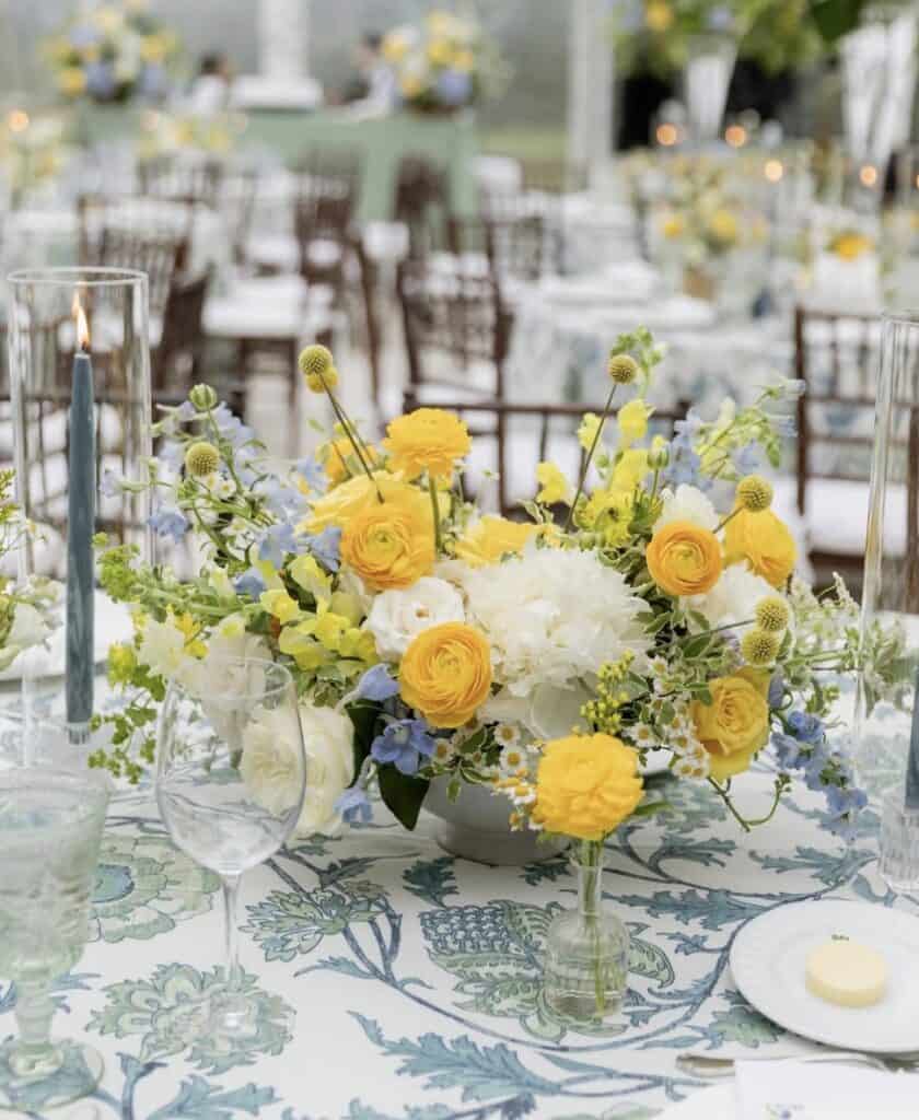 Wedding table centerpiece with yellow flowers and blue accents
