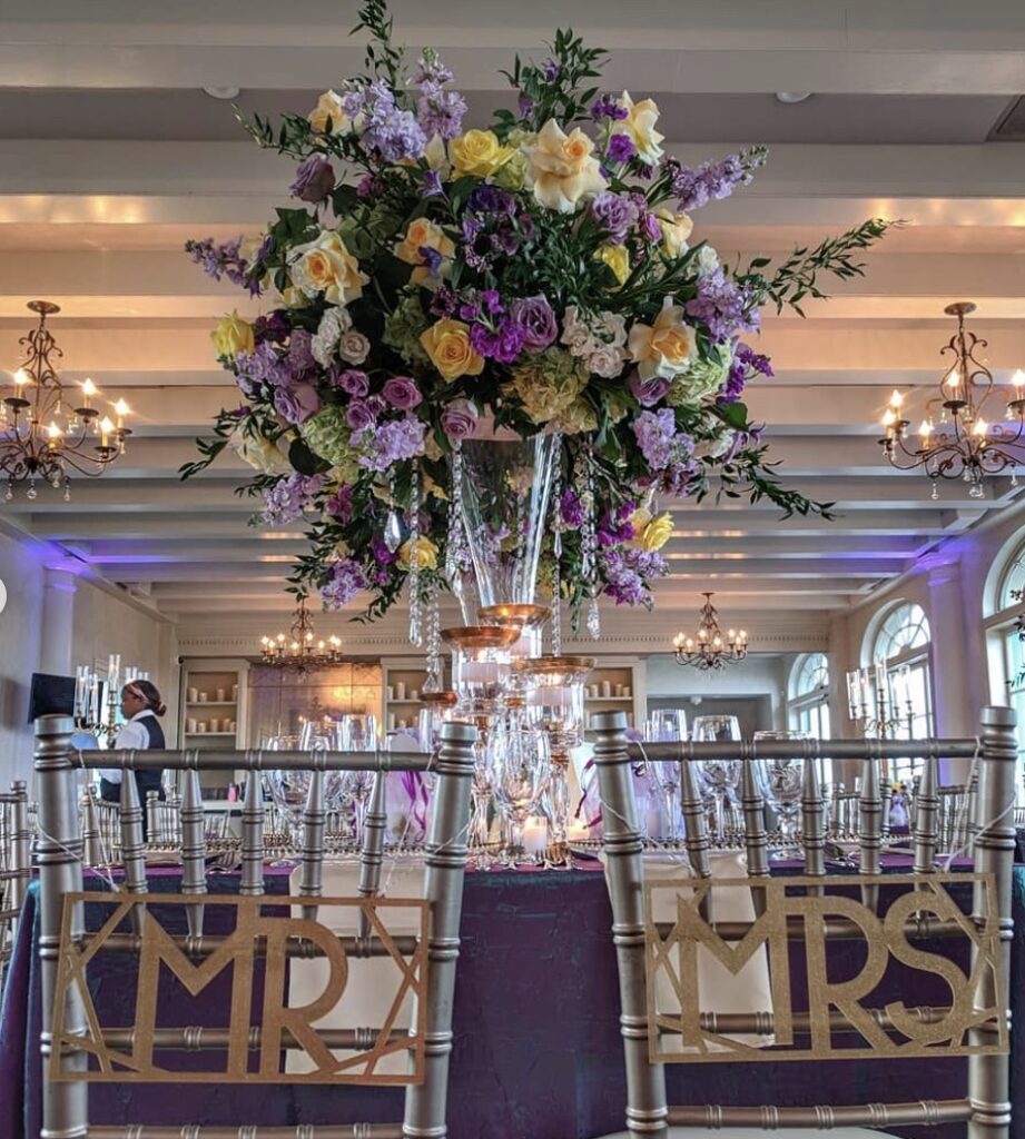 Lavish floral centerpiece with purple and yellow flowers and chandelier decor