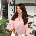 Woman in pink ruffled blouse and white pants, spring outfit inspiration