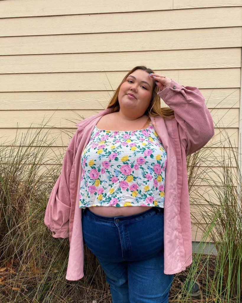Plus size woman in floral crop top and pink jacket, spring casual.