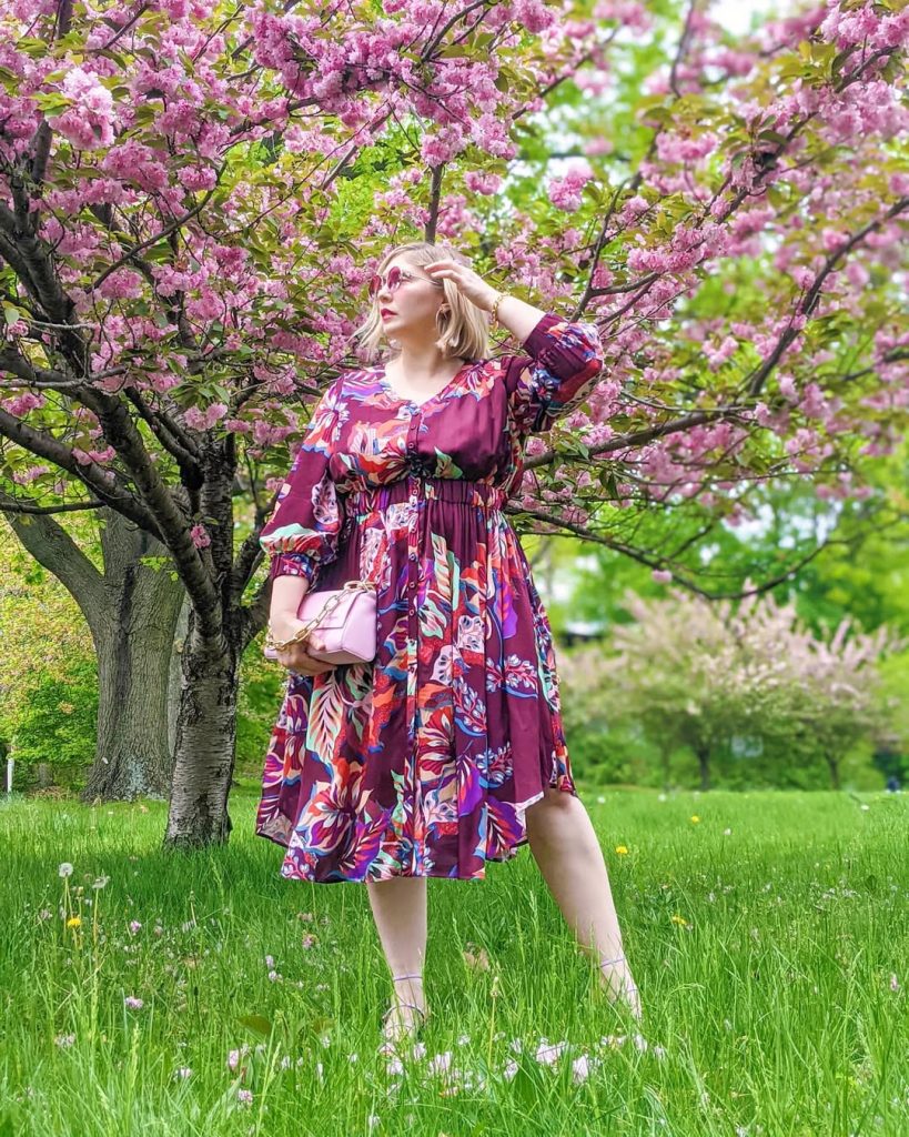 Plus size woman in jeans and boho blouse with straw hat, relaxed spring style.