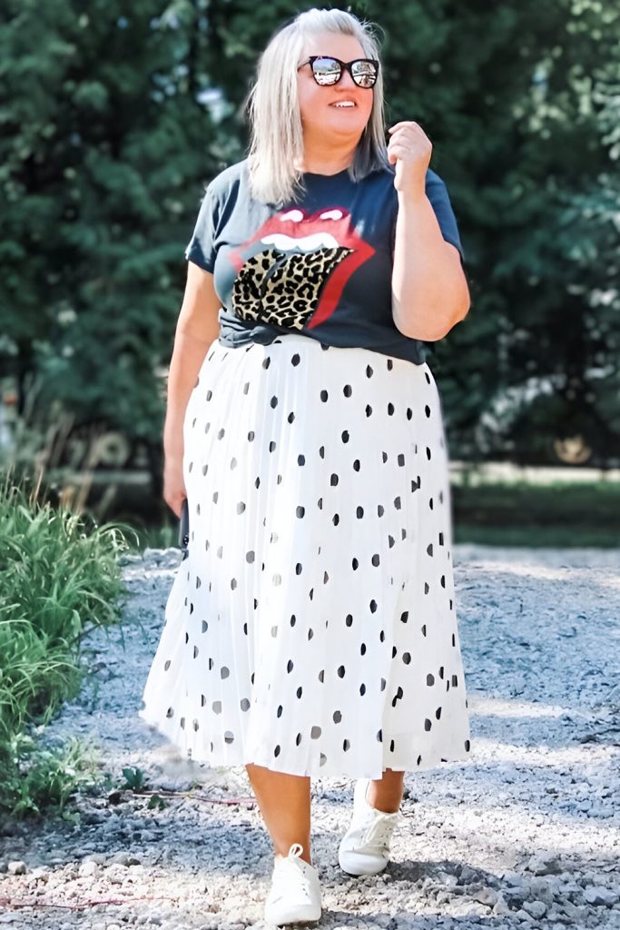 Plus size woman in graphic tee and polka dot skirt, playful spring style.