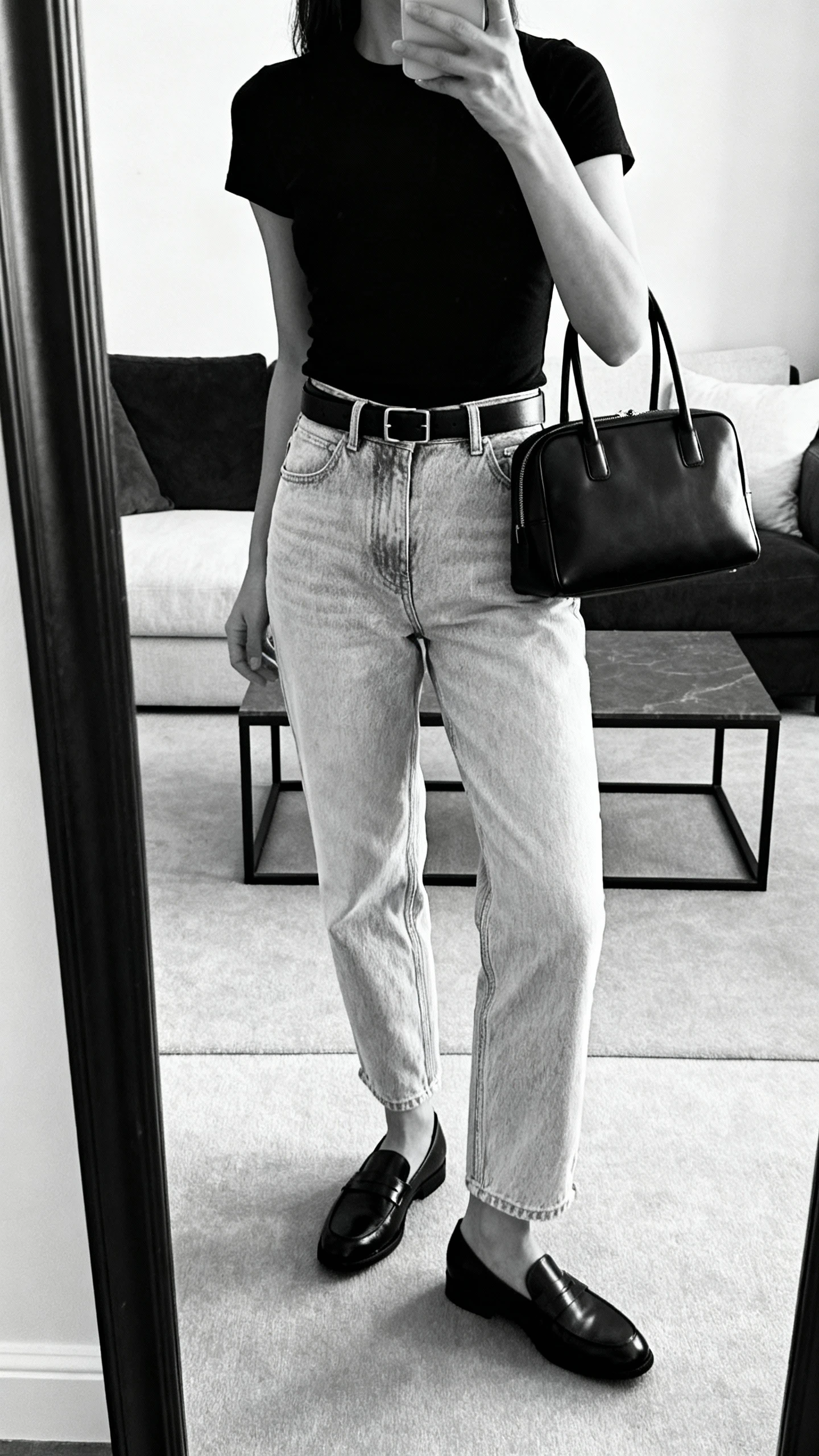 Monochrome outfit with black top, light jeans, and black loafers