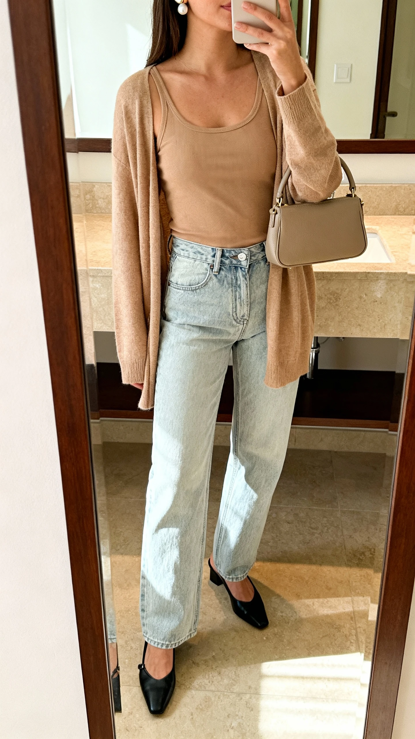Woman in light jeans, beige top, and cardigan with a neutral handbag