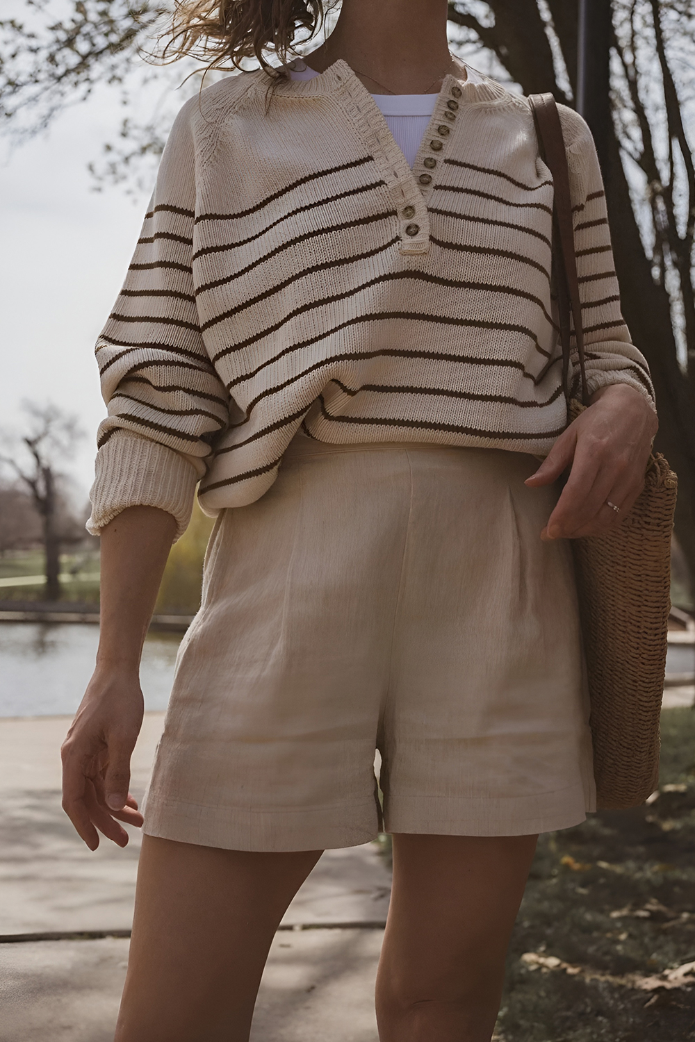 Woman in a striped sweater with shorts and a woven bag