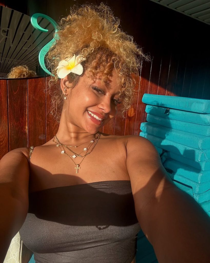 Curly hairstyle with floral accent, playful, vibrant spring look.