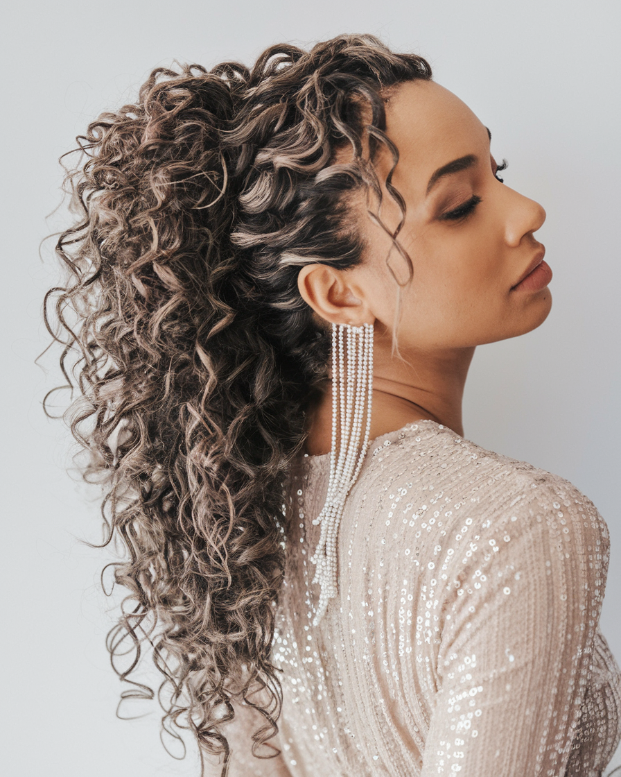 Textured curly ponytail with statement earrings, modern bridal style