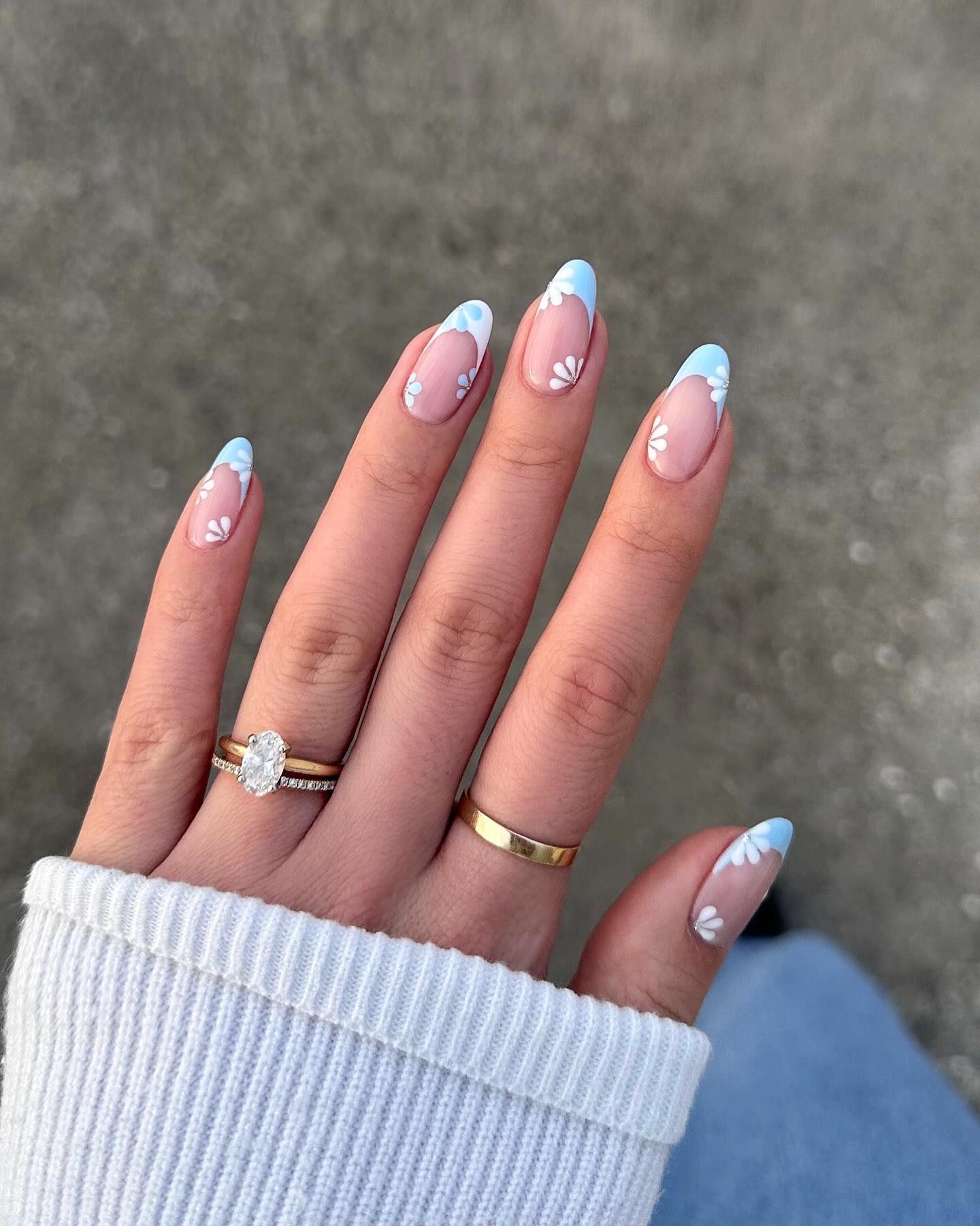Floral blue French tips with white flowers on almond nails