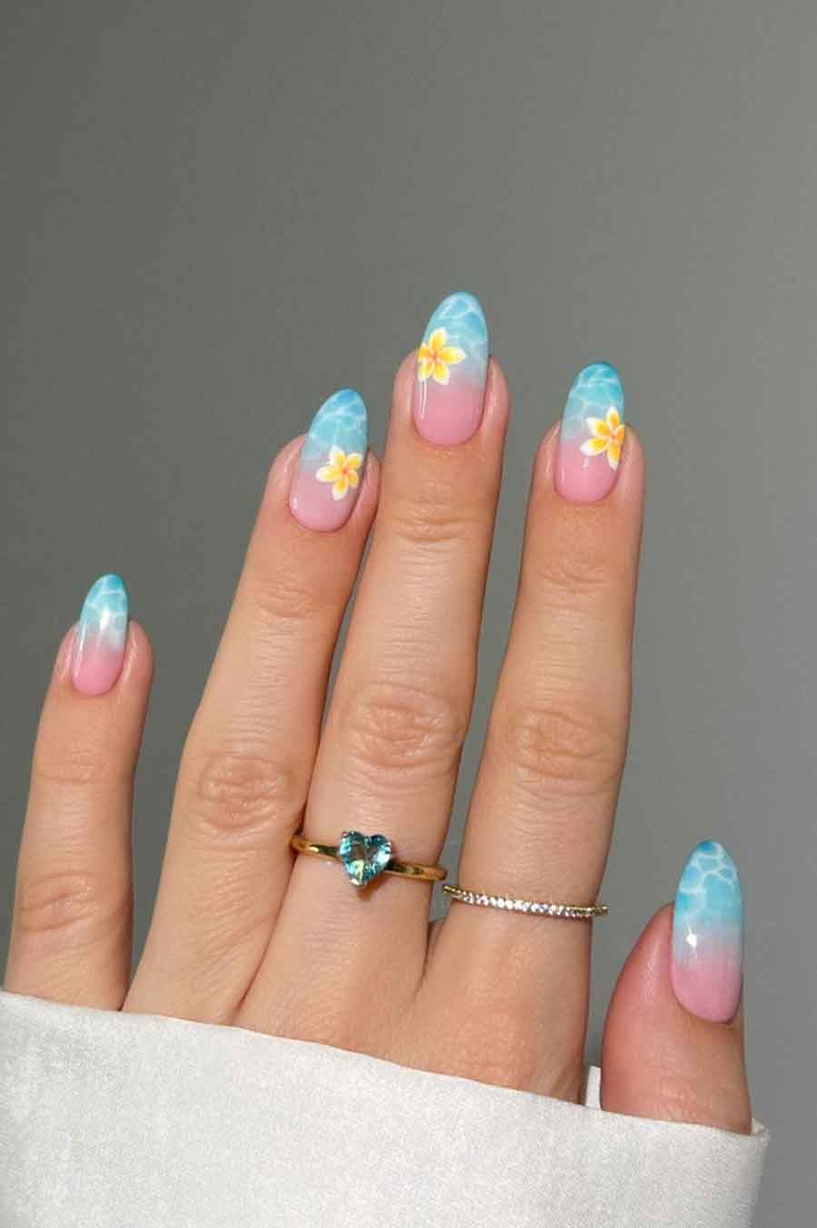 Oceanic blue ombre French tips with floral accents on almond nails