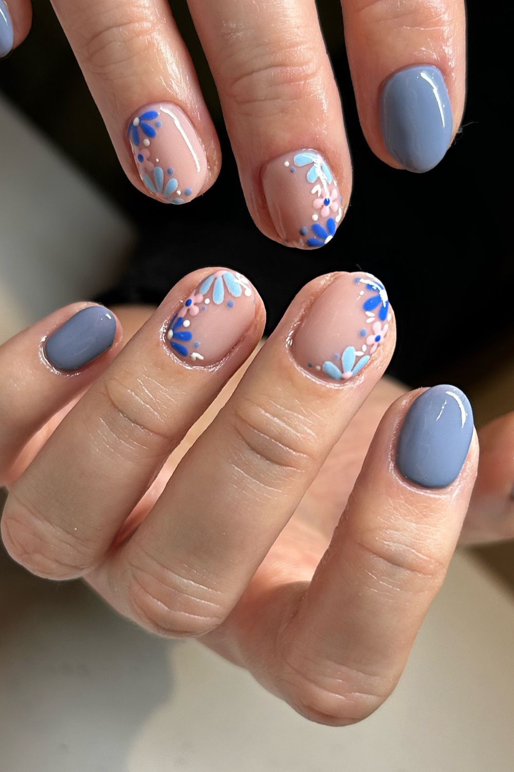 Artistic blue and nude nail design with intricate patterns