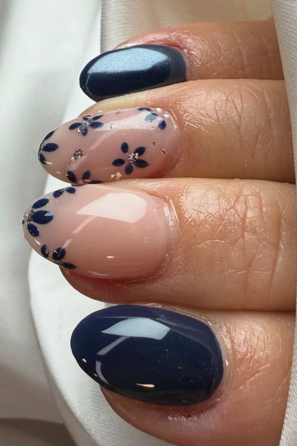 Navy and nude nails with floral accents on oval shape