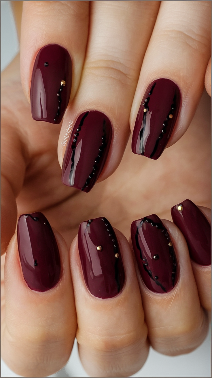 Burgundy nails with black and gold accents