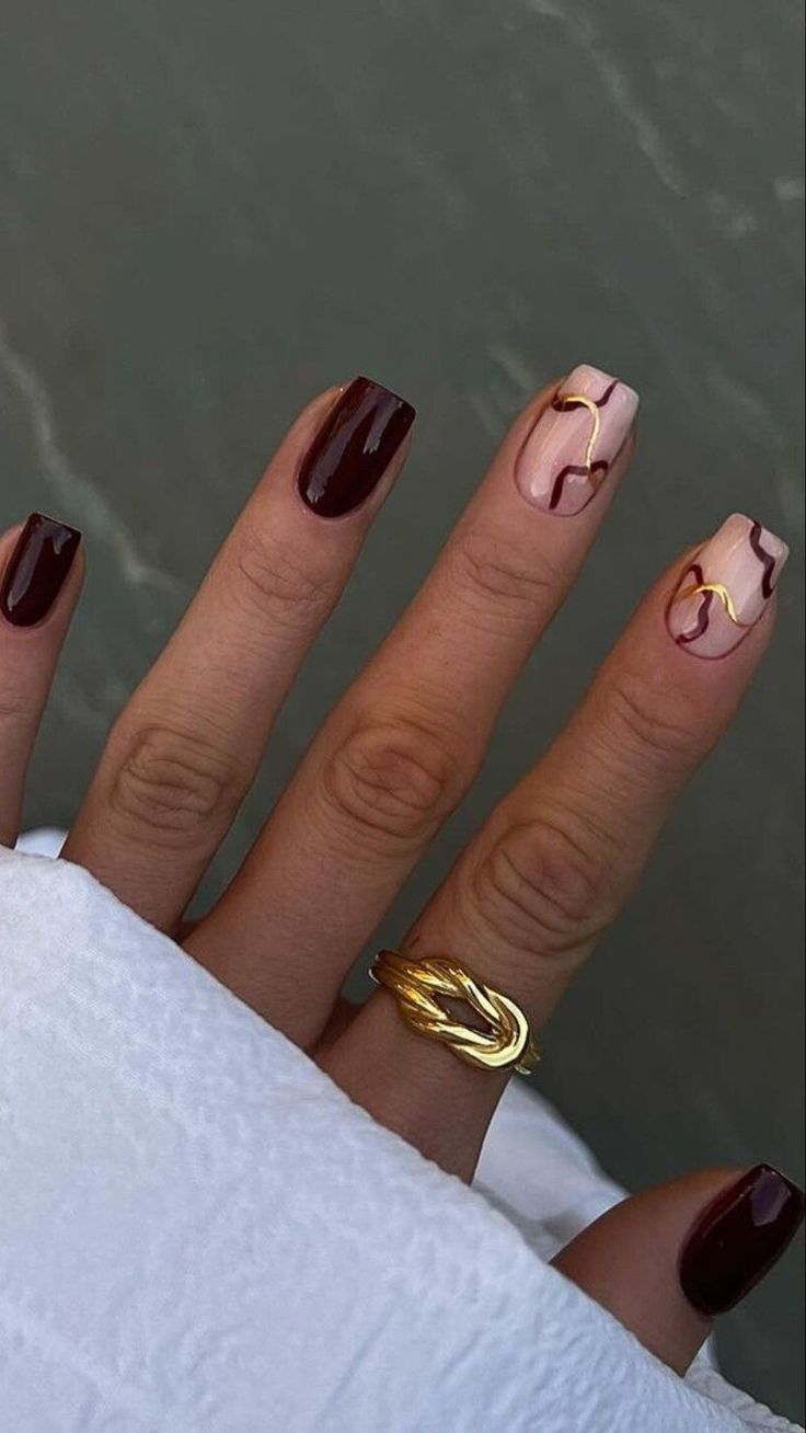 Burgundy and nude marble nails with gold accents