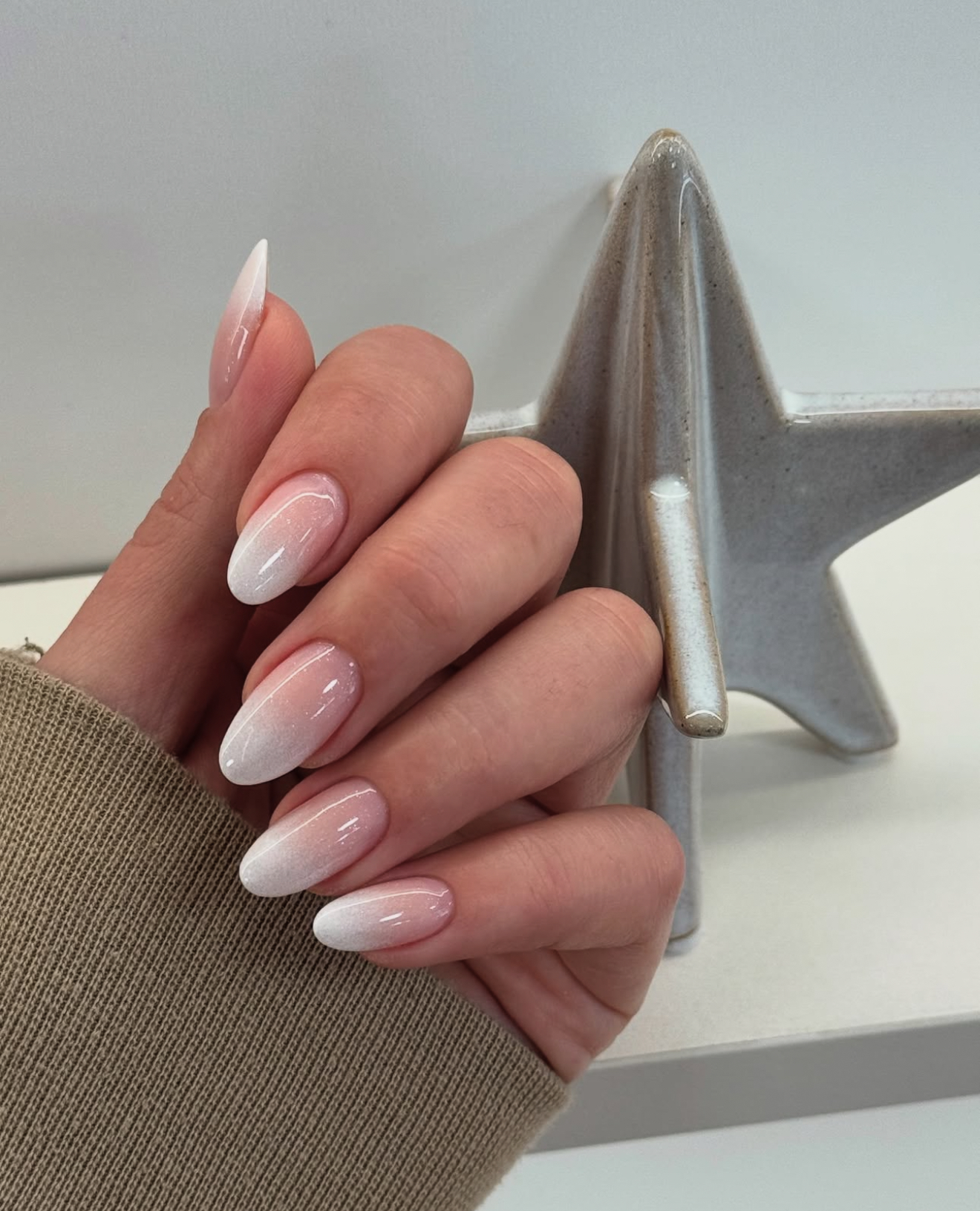 Soft pink ombre on almond-shaped nails, trending nail style.