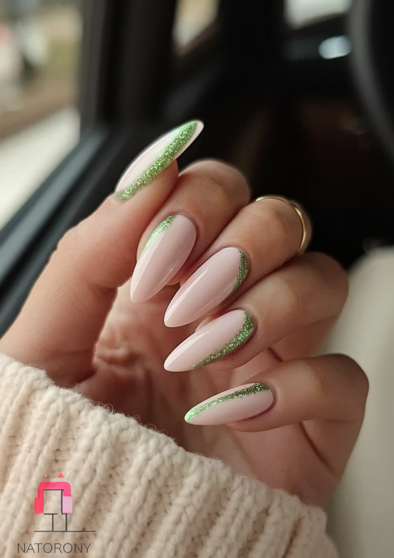 Modern French manicure with green glitter tips on almond nails.