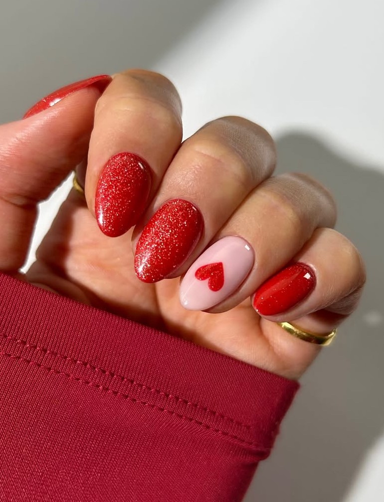 Red glitter nails with heart design, romantic touch.