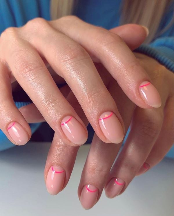 Nude nails with neon pink half-moons.