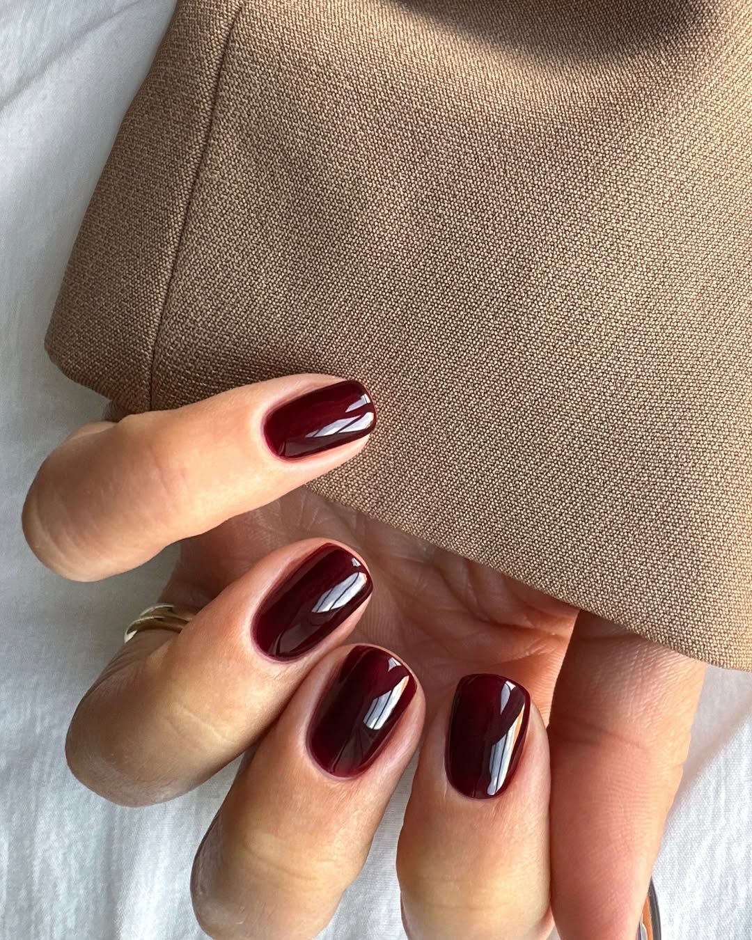 Deep burgundy short round nails, sophisticated look.