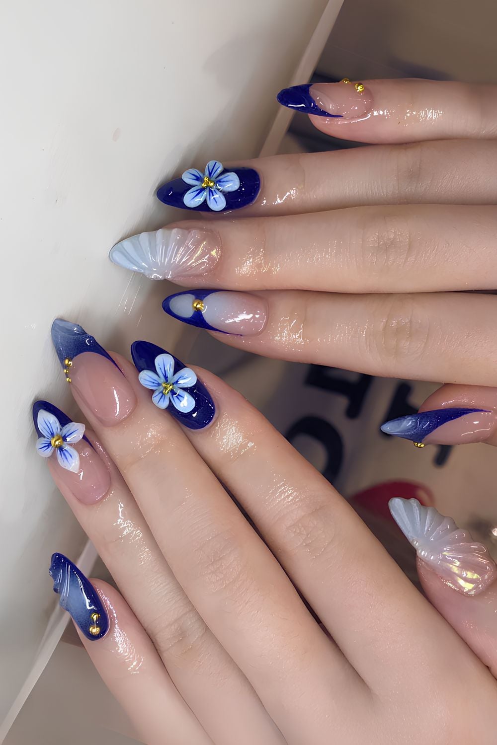 Blue and gold flower nail art with dark tips.