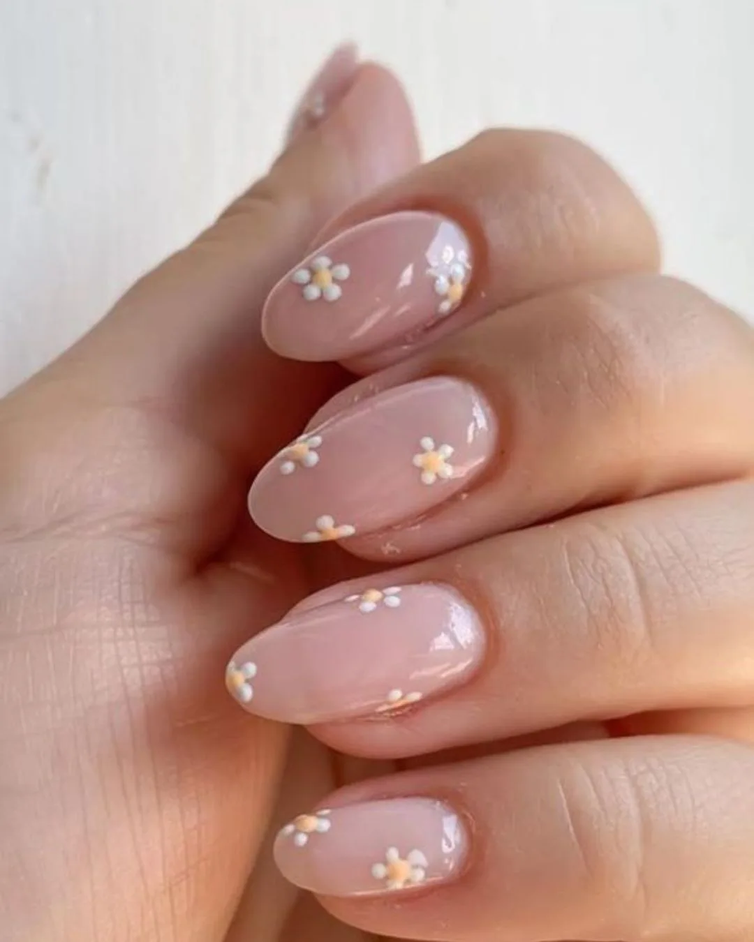 Soft pastel daisy nail art on a nude base.