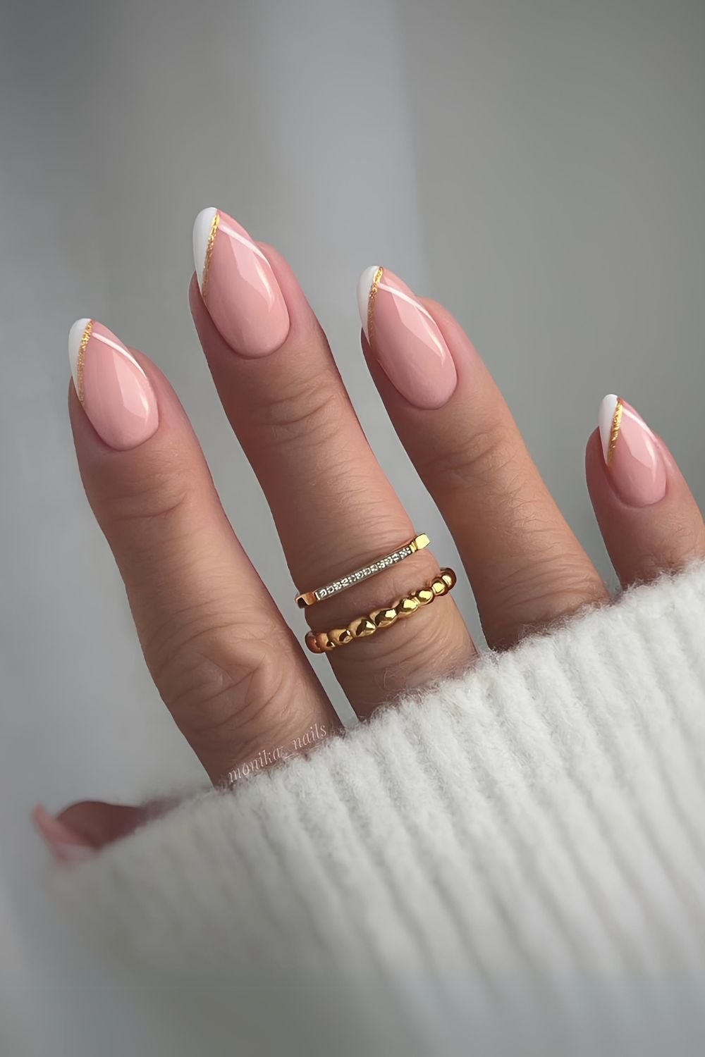 Almond-shaped nails with gold-accented French tips, showcasing luxurious and modern nail art.