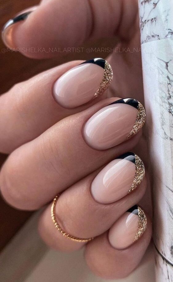 Oval nails with gold and black glitter tips, sophisticated and glamorous.