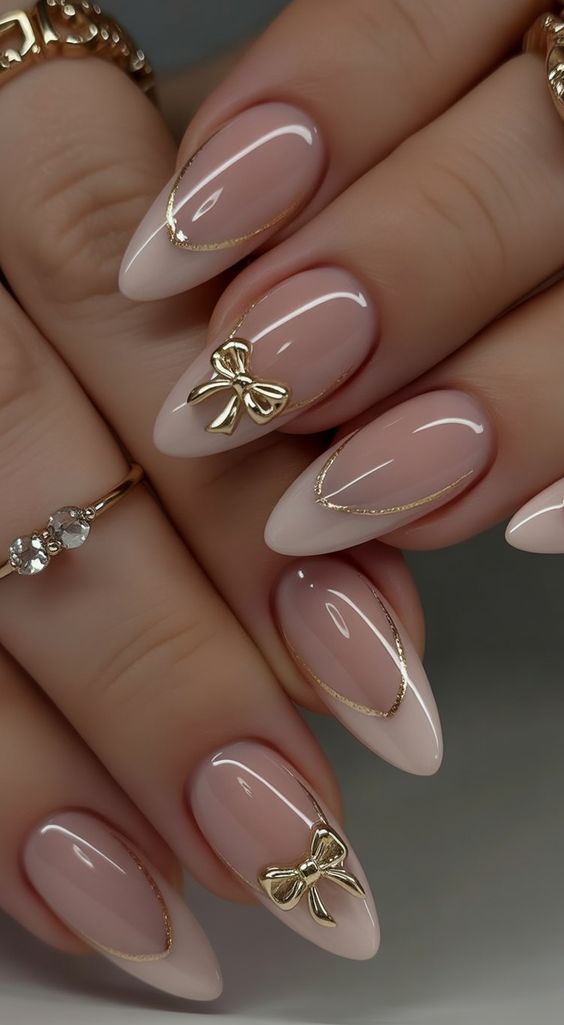Almond nails with gold bow French tips, chic and luxurious.