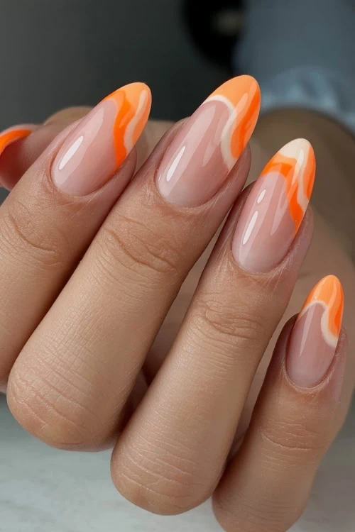 Orange swirl nails with a nude base, vibrant and dynamic.