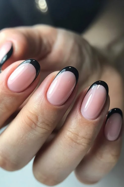 Black French tips on oval nails, chic and bold.