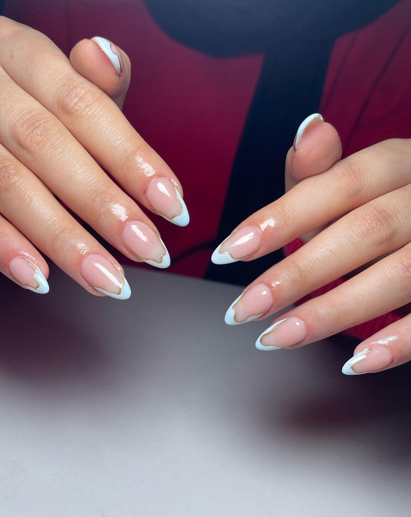White and gold French tips on almond nails, elegant and luxurious.
