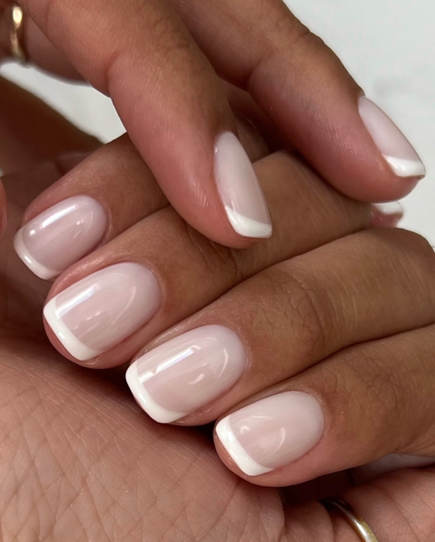 Soft pink French tips on short oval nails, elegant and subtle.