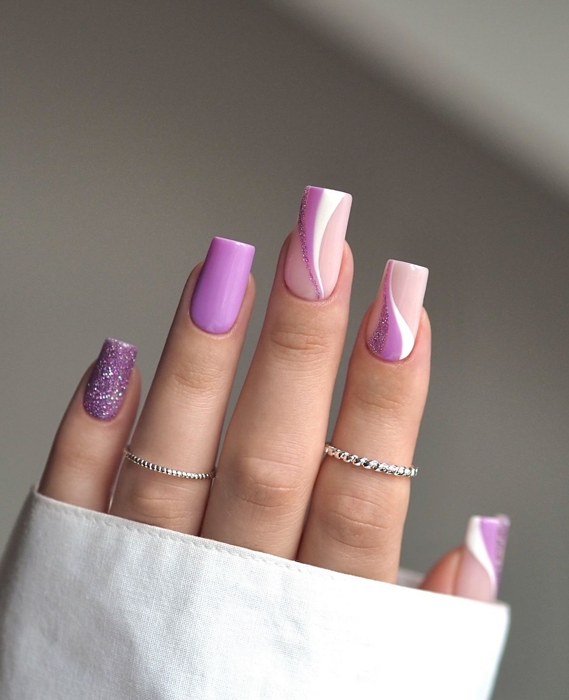 Lavender nails with white swirls and glitter accents