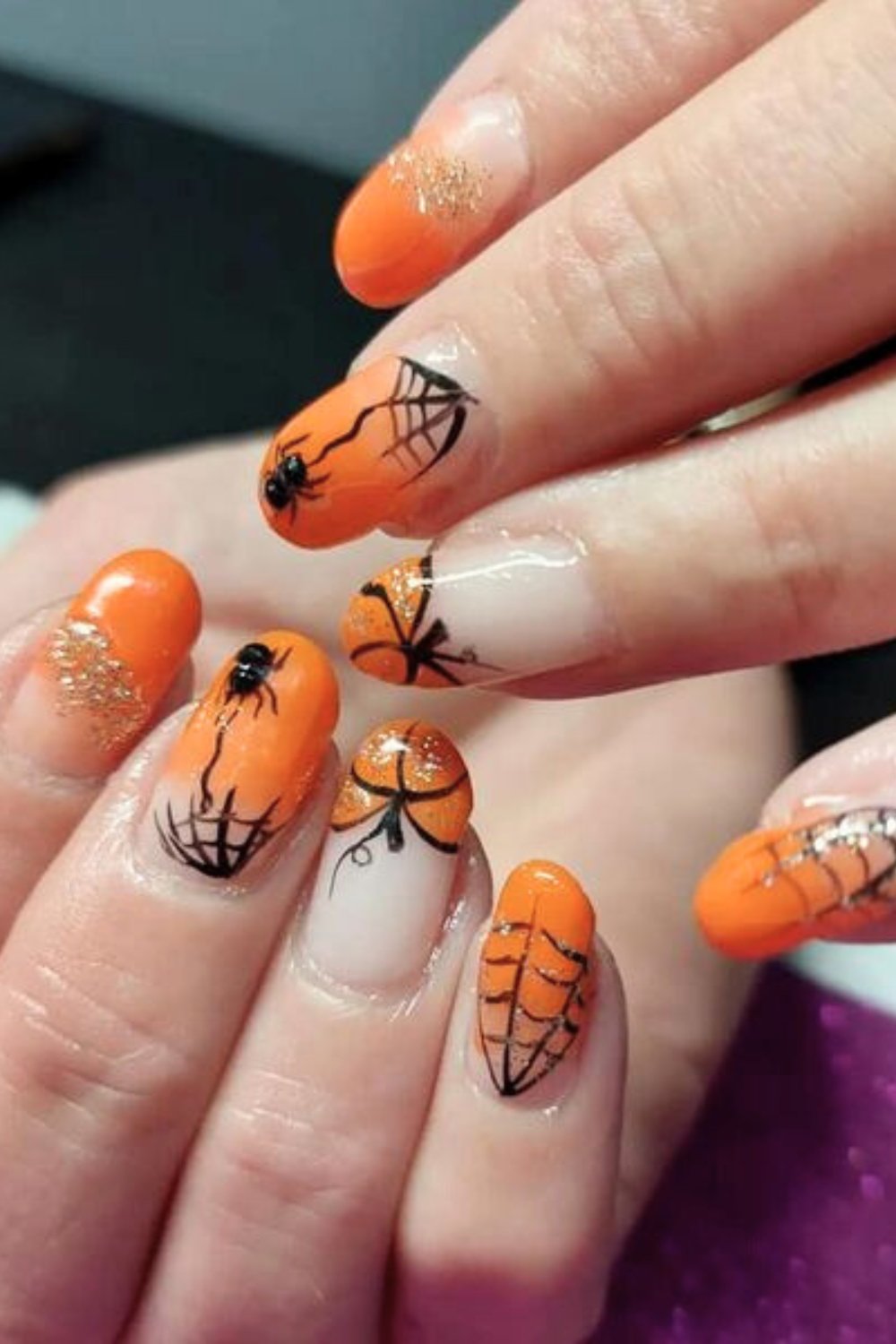 Halloween-themed orange nails with spider web design