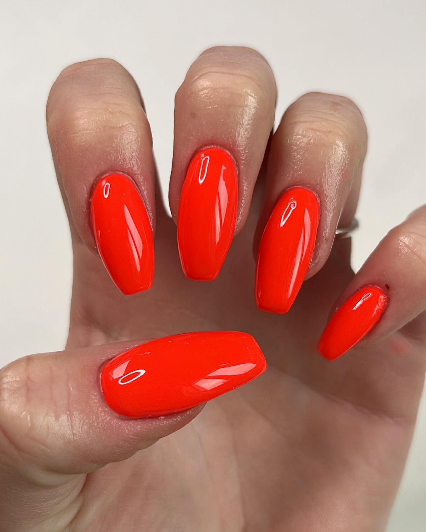 Glossy red-orange nails on medium length
