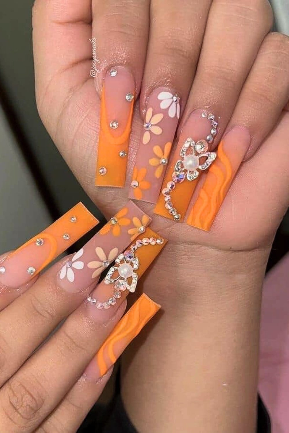 Long nails with orange floral design and jewels