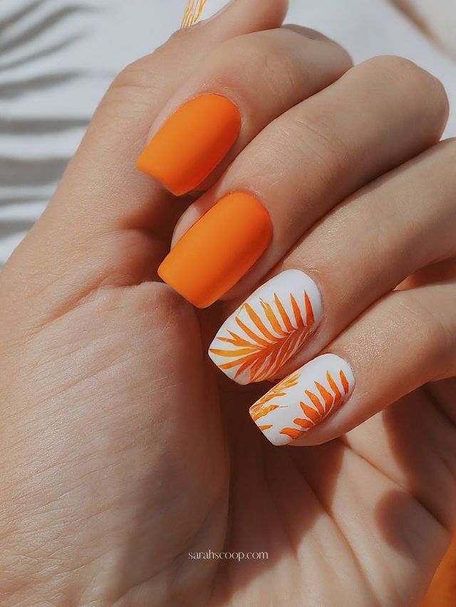 Matte orange nails with tropical leaf design