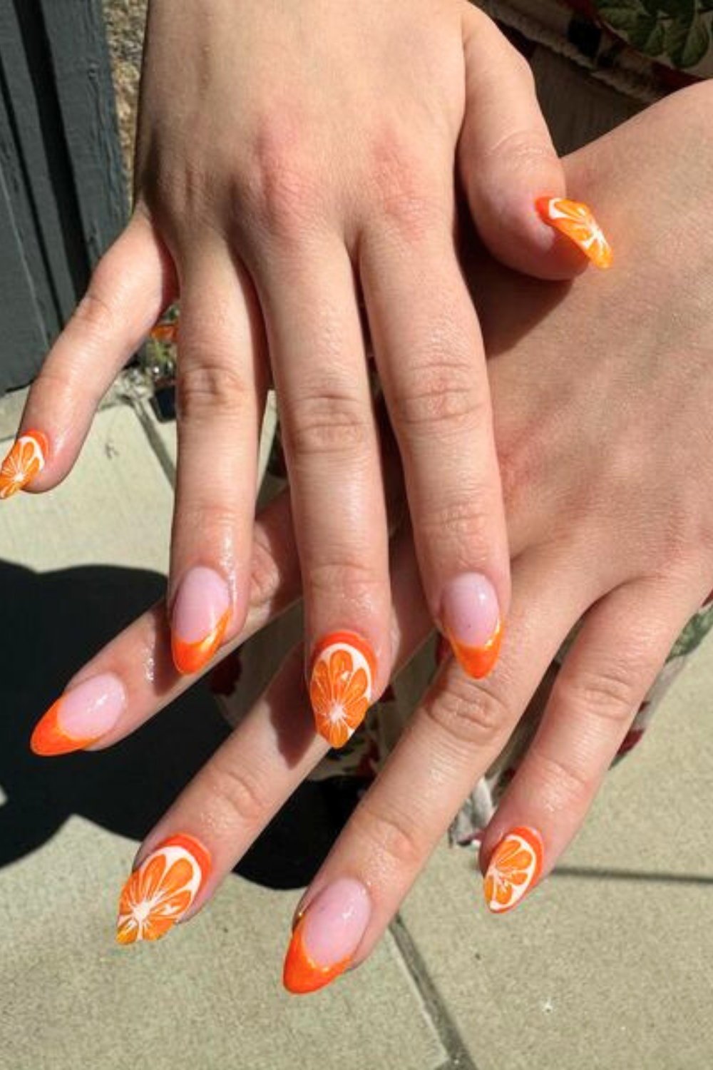 Orange French tips with floral art on almond nails