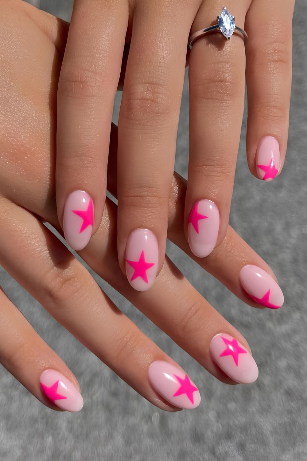Pink star nails on nude oval base.