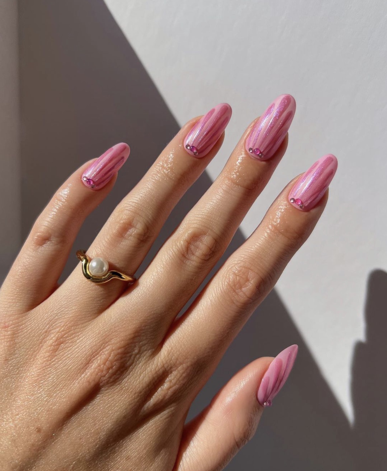 Metallic pink striped almond nails with rhinestones.