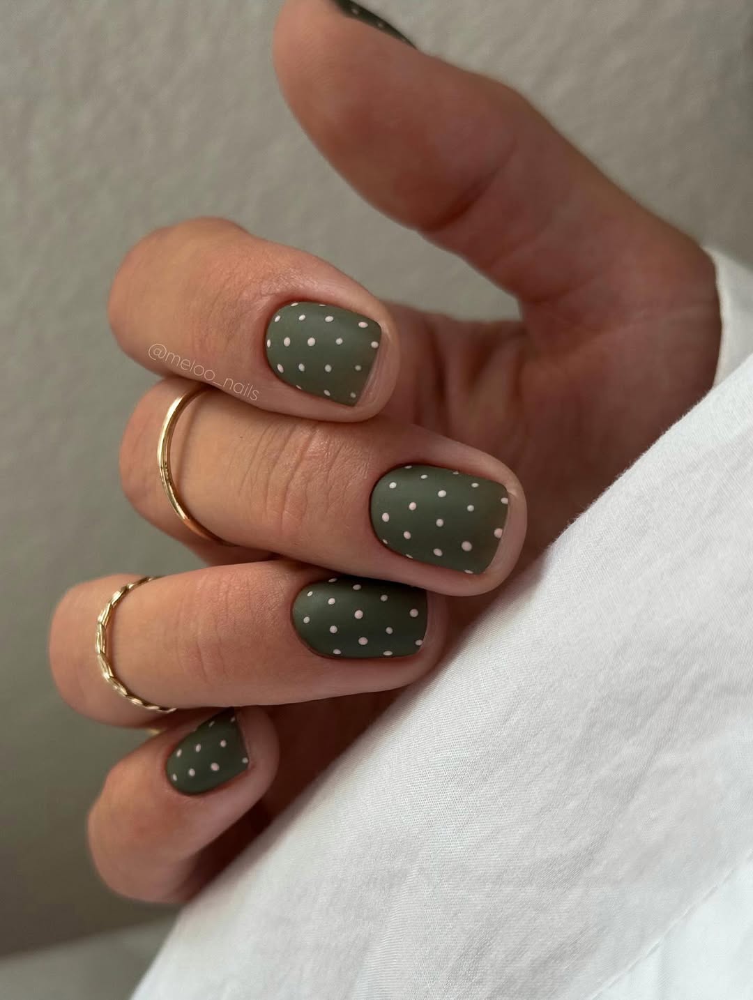 Green nails with white polka dots