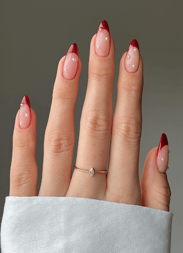 Red French tips with pearls on long stiletto nails.