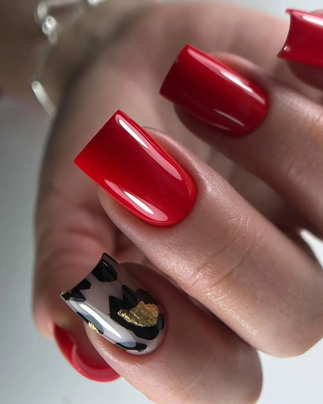 Vibrant red nails with artistic flair and gold accents