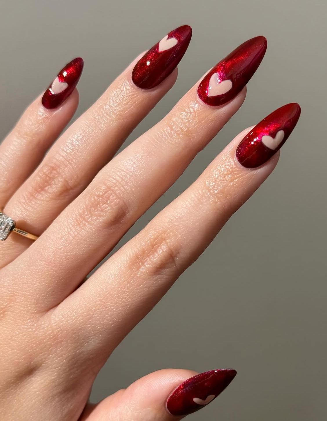 Romantic red nails with heart details and stiletto shape