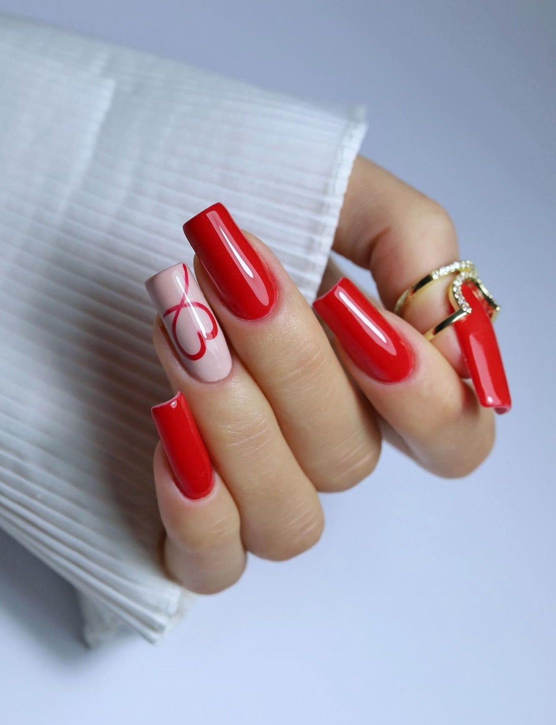 Glossy red nails with heart accent and square shape