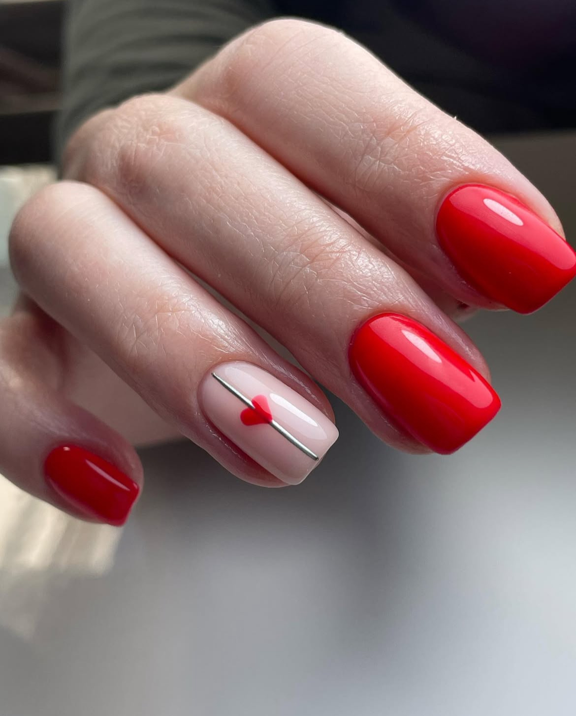 Red nails with heart accent, short oval shape