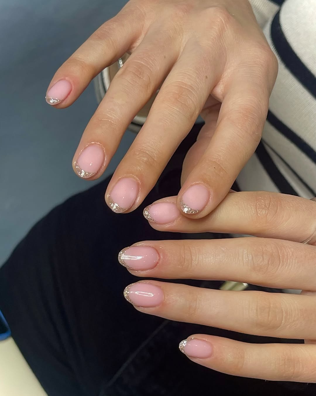 Short square nails with pink polish and glitter French tips
