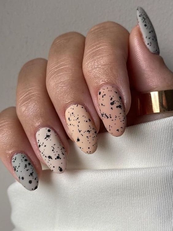 Short almond nails with speckled black and nude design